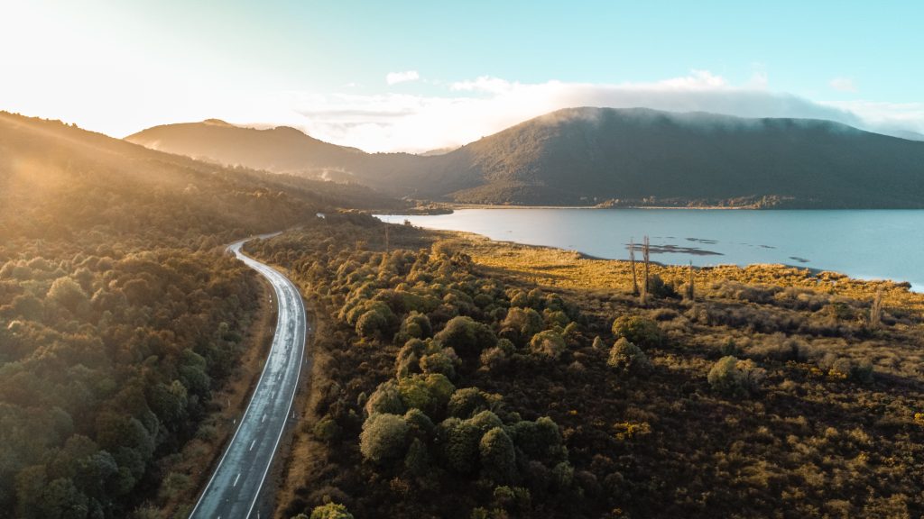 Road going through the countryside with sea and hills in the background.